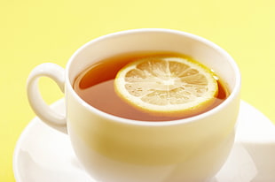 white ceramic teacup with sliced lemon
